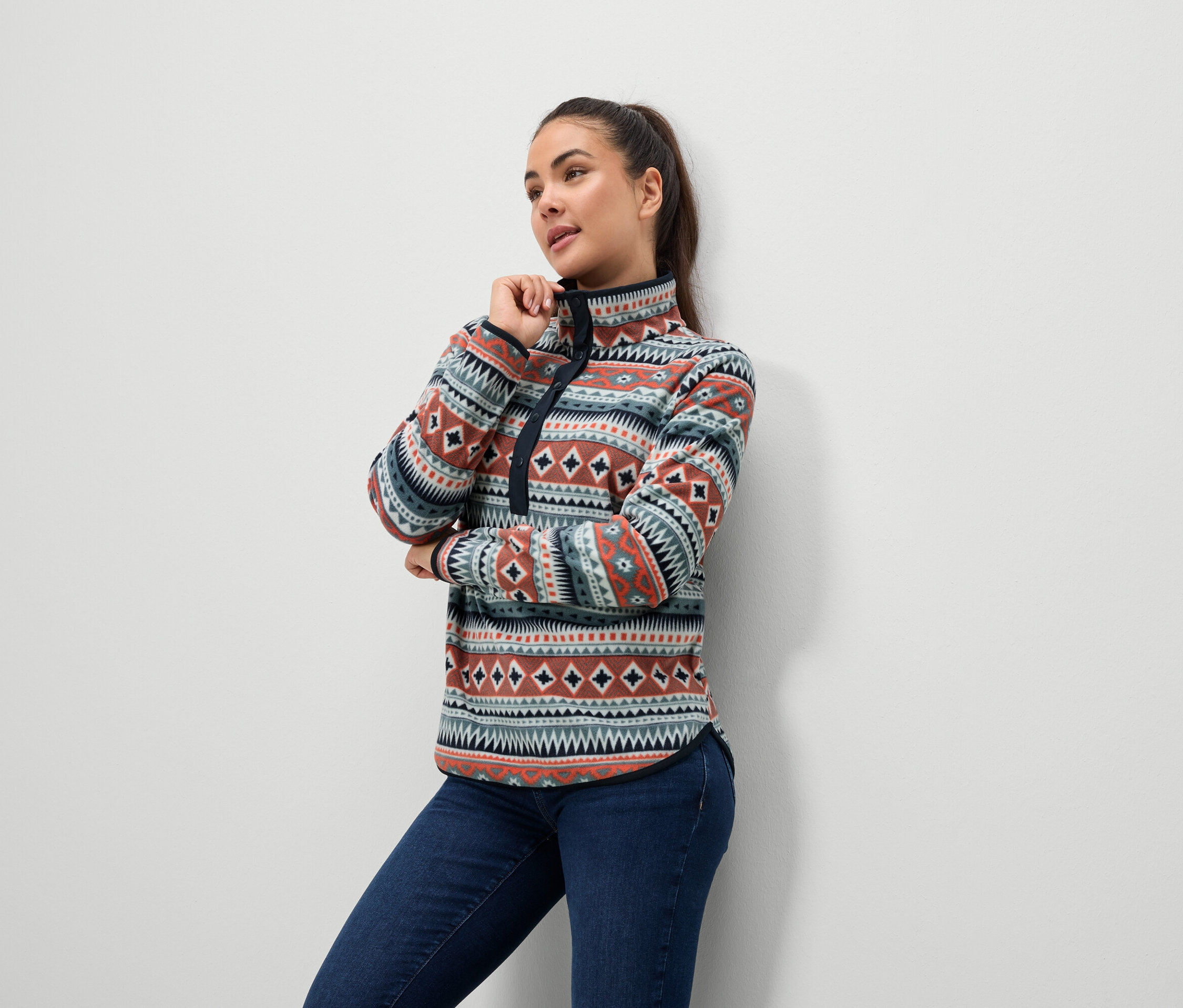 Une femme porte un pull en polaire à motifs et un jean.