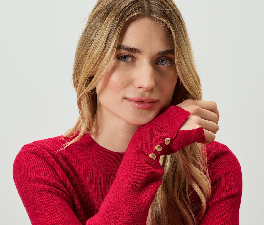 Portrait d'une femme blonde portant un pull rouge.