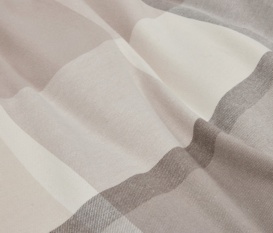 Gros plan d'un tissu à carreaux dans des tons beige et gris.
