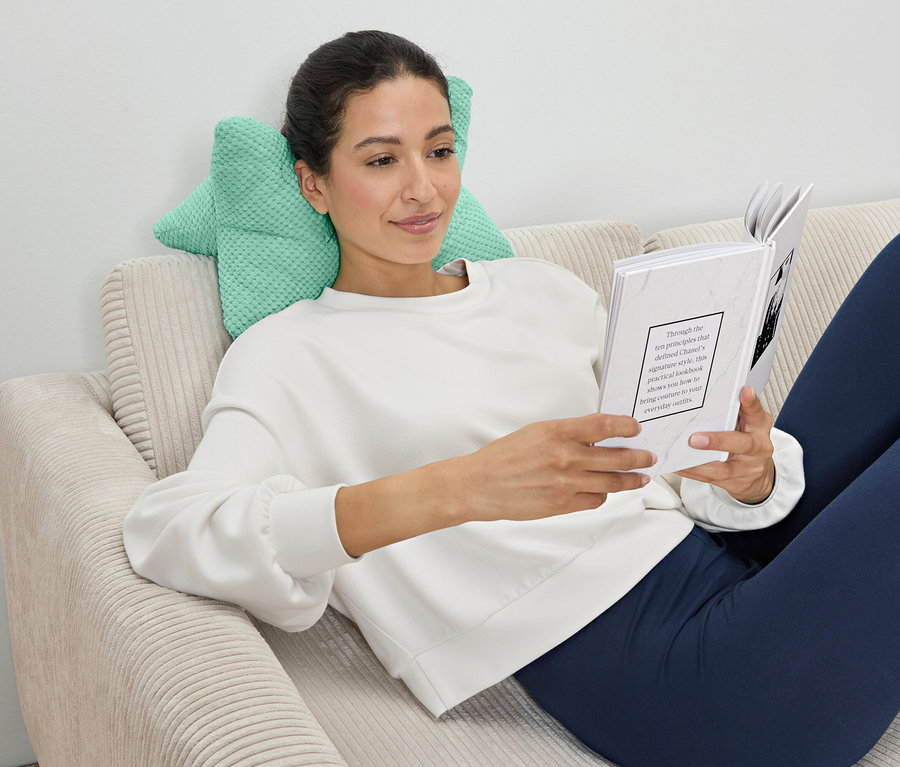 Femme lisant un livre, appuyée sur un coussin de lecture.