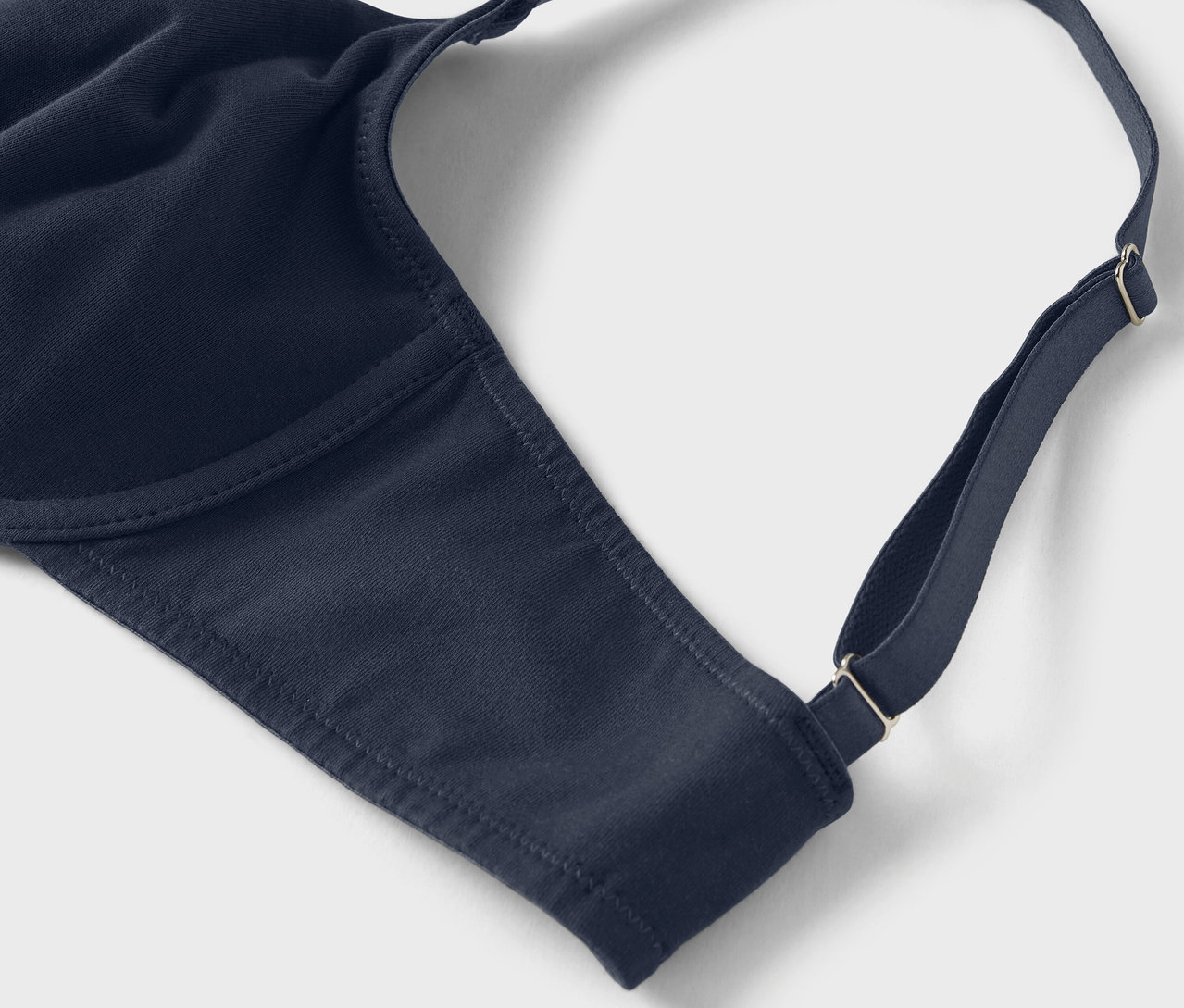 Gros plan d'un soutien-gorge bleu marine avec bretelles réglables sur un fond clair.