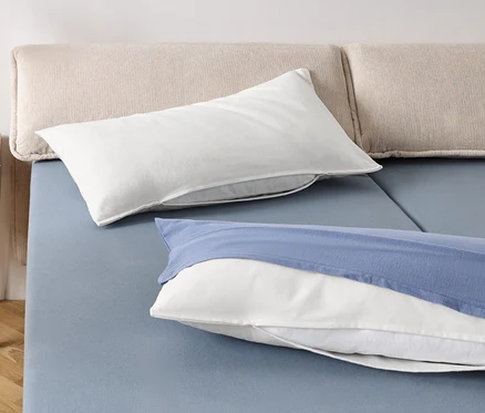 Deux oreillers blancs et un oreiller blanc avec une taie bleue sur un lit bleu.