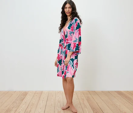 Femme debout de profil portant une robe de chambre à motif floral.