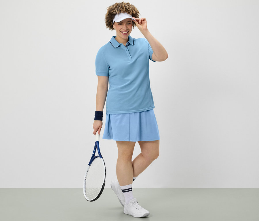 Femme tenant une raquette de tennis, portant une jupe de sport bleu clair et un polo technique.