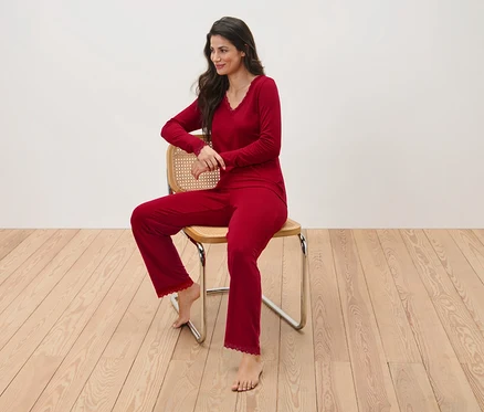Une femme assise sur une chaise en pyjama rouge.