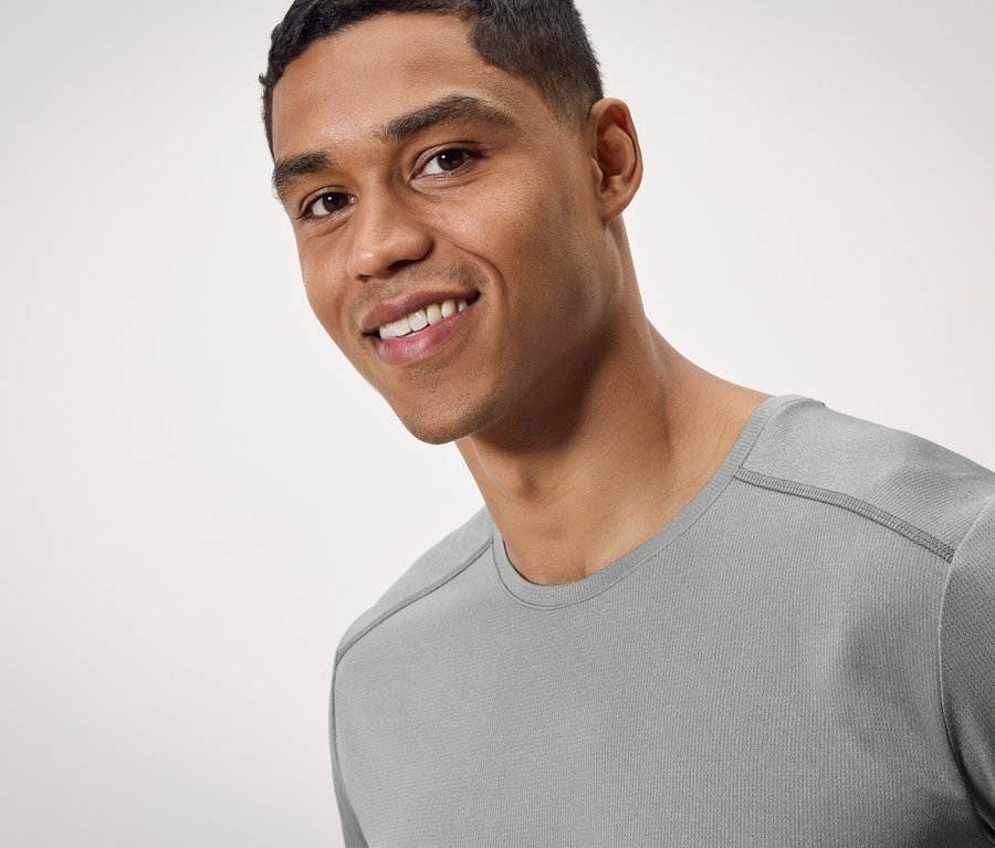 Portrait d'un homme souriant portant un t-shirt gris.