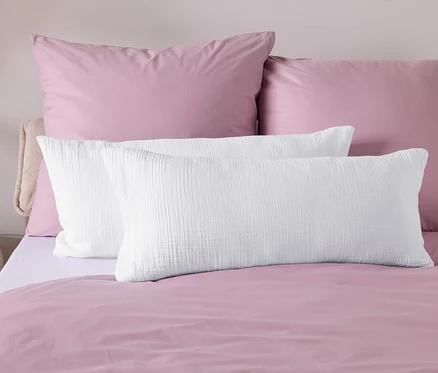 Gros plan de linge de lit avec une couette rose et des oreillers blancs.