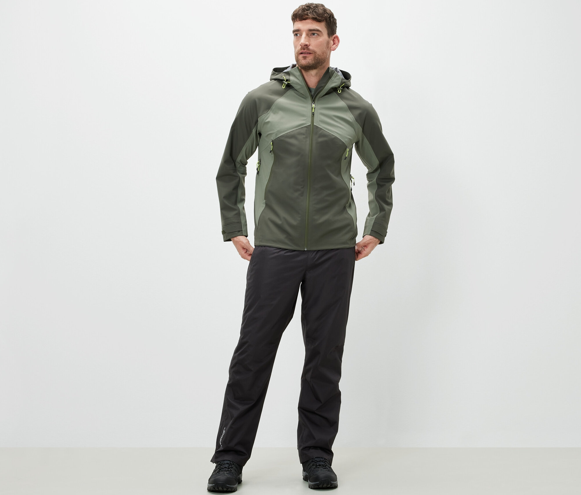 Un homme debout portant un pantalon de pluie high-tech et une veste.