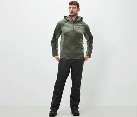 Un homme debout portant un pantalon de pluie high-tech et une veste.