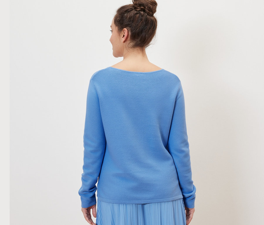 Femme portant un pull en maille bleu ciel.