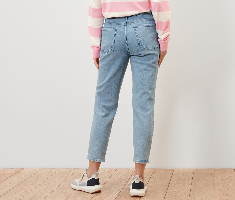Vue arrière d'une femme portant un jean Mom ‒ Coupe « Kira », un haut rayé et des baskets.