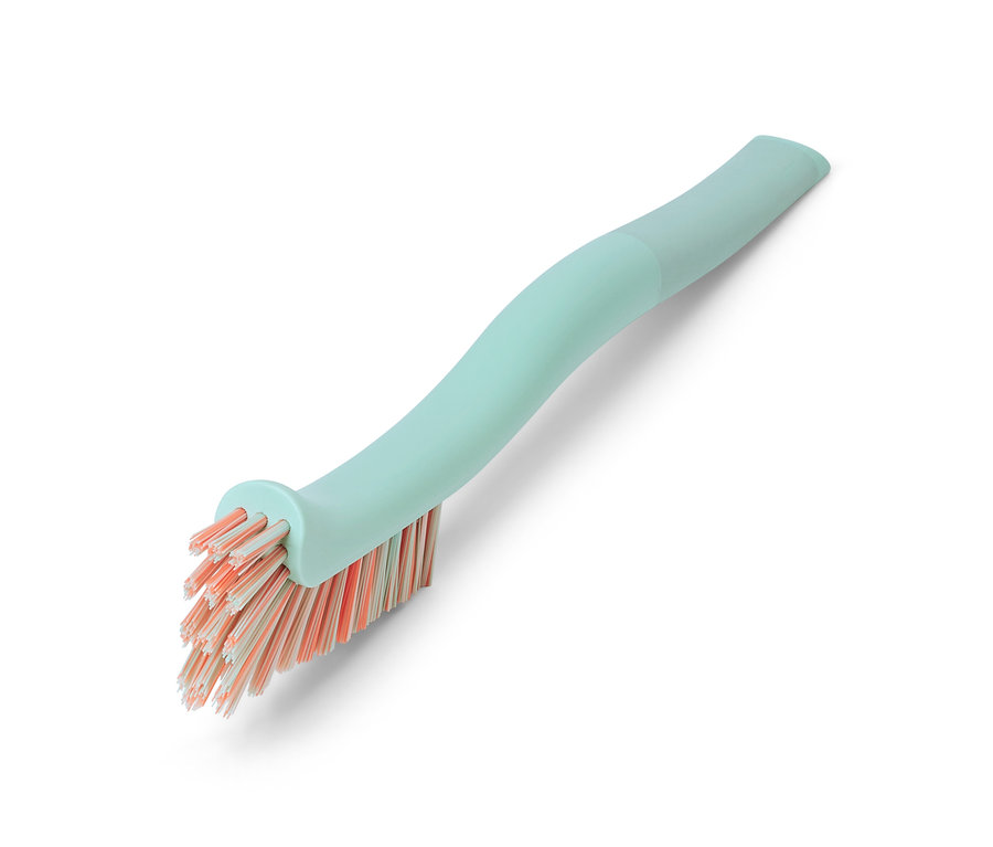 Une brosse à joints avec un manche vert d'eau et des poils orange est posée en diagonale sur un fond blanc.