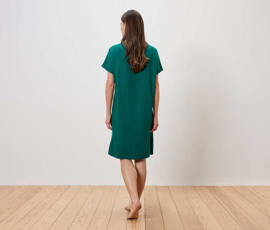 Femme vue de dos, pieds nus, portant une robe verte ample.