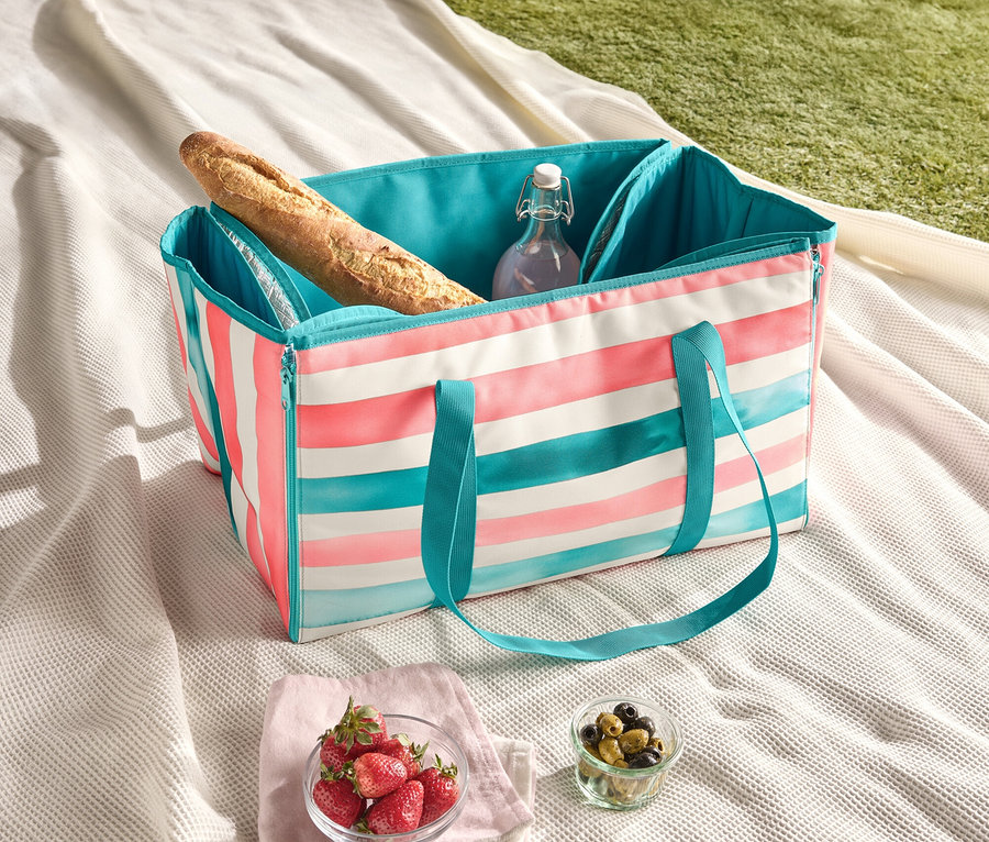 Couverture de pique-nique avec sac isotherme rayé, baguette, bouteille d'eau, fraises et olives.