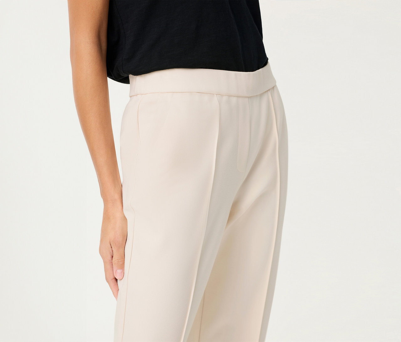 Une femme porte un pantalon en lin Olsen cropped avec un haut noir sur un fond blanc.
