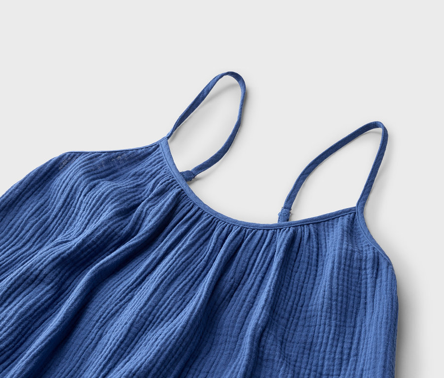 Gros plan d'une robe à bretelles bleue avec des bretelles réglables sur un fond neutre.