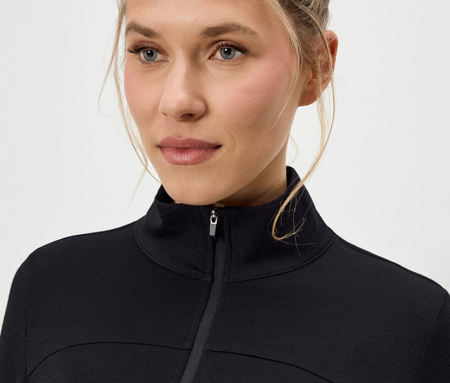 Gros plan d'une femme aux cheveux blonds portant une veste noire zippée.