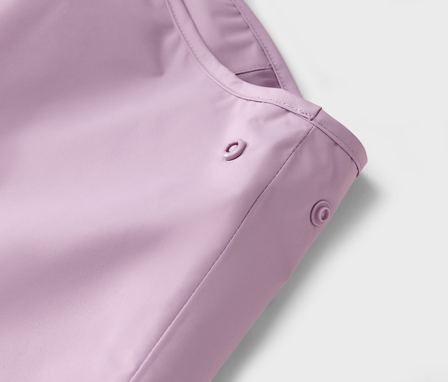 Gros plan sur un imperméable violet avec des boutons-pression.