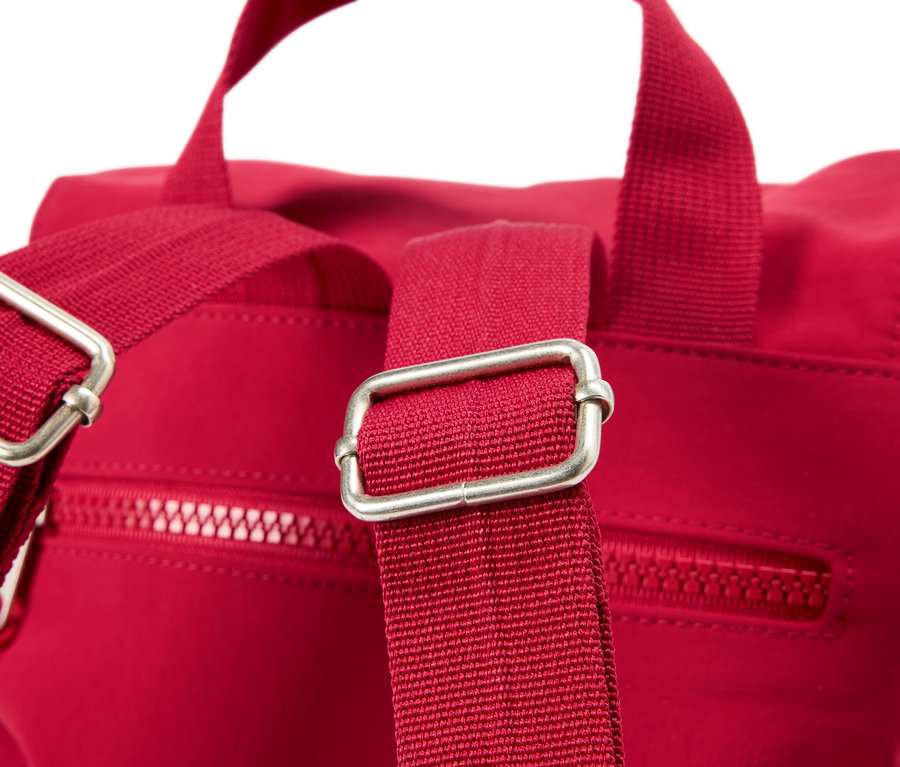 Gros plan d'un sac à dos rouge avec des boucles argentées sur les bretelles.