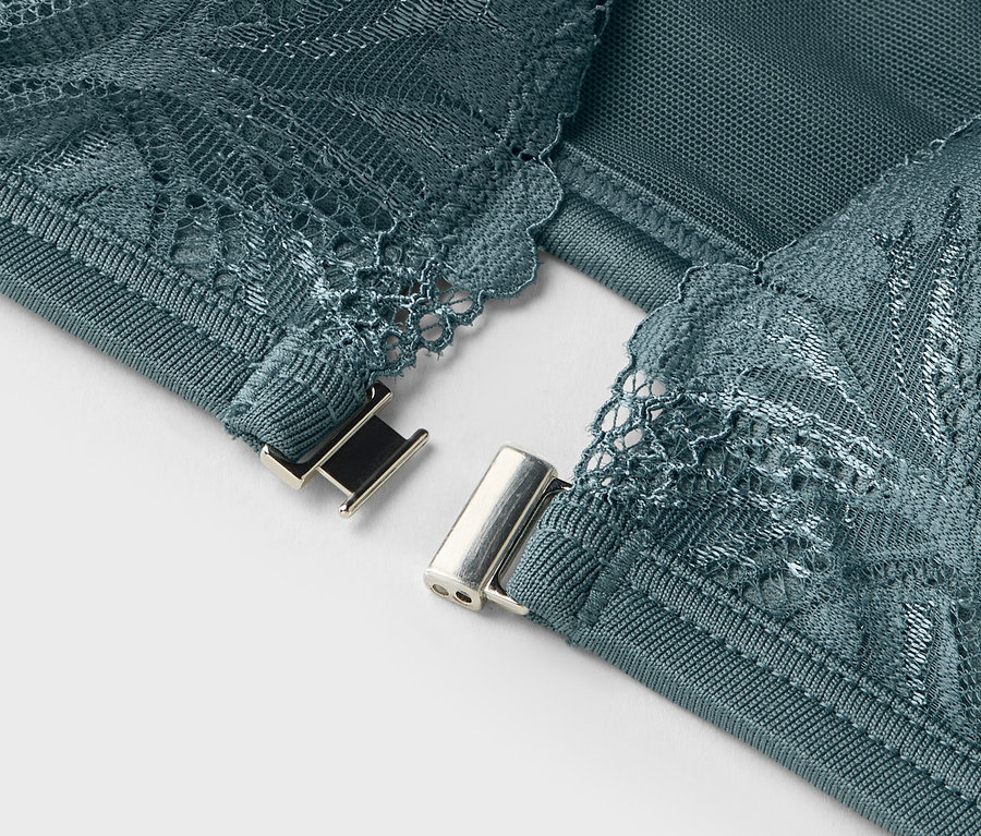 Gros plan sur les détails d'un soutien-gorge turquoise avec de la dentelle et une fermeture argentée.