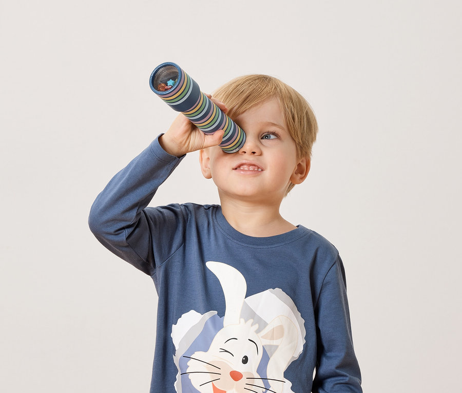 Un garçon blond regarde dans un kaléidoscope.