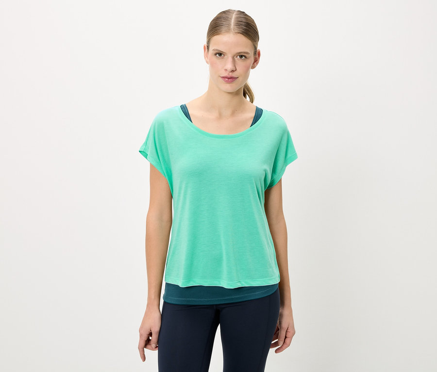 Femme portant un t-shirt vert et un legging bleu.