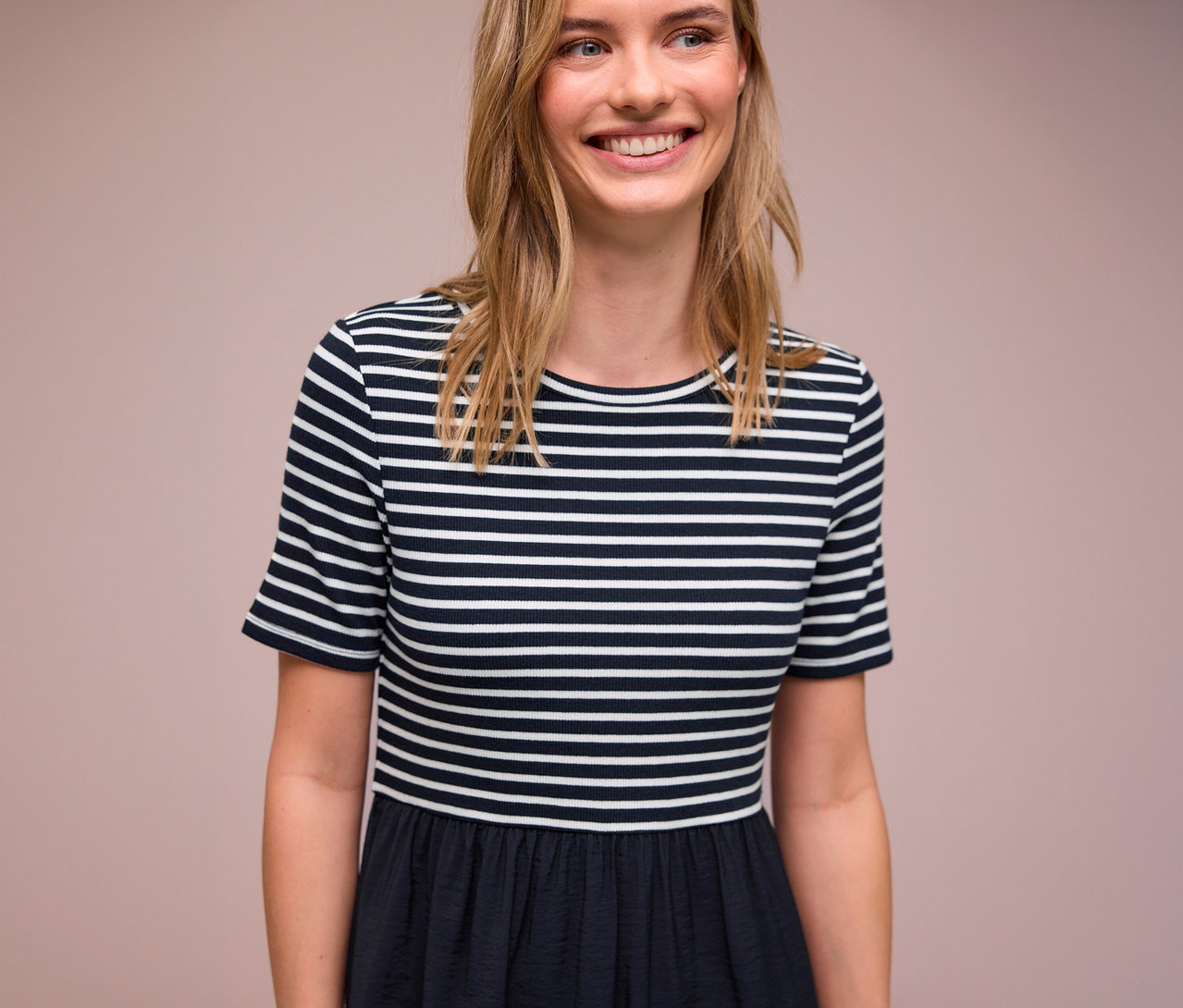 Une femme souriante porte une robe Street One à rayures bleues et blanches.