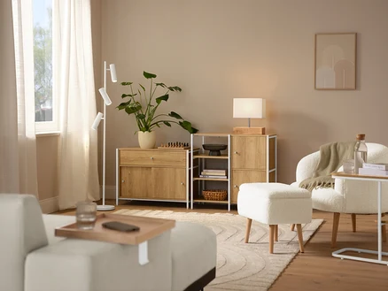 Scène d'intérieur avec un tapis beige »Cosmo«, un fauteuil bouclette avec pieds en bois et une lampe de table avec pied en bois.