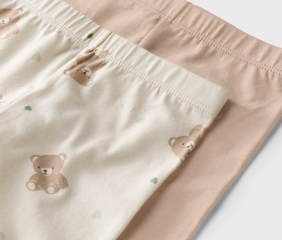 Gros plan sur deux leggings, l'un beige avec un motif d'ours, l'autre uni marron clair.