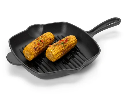 Deux épis de maïs avec des épices sont posés dans une poêle à griller noire.