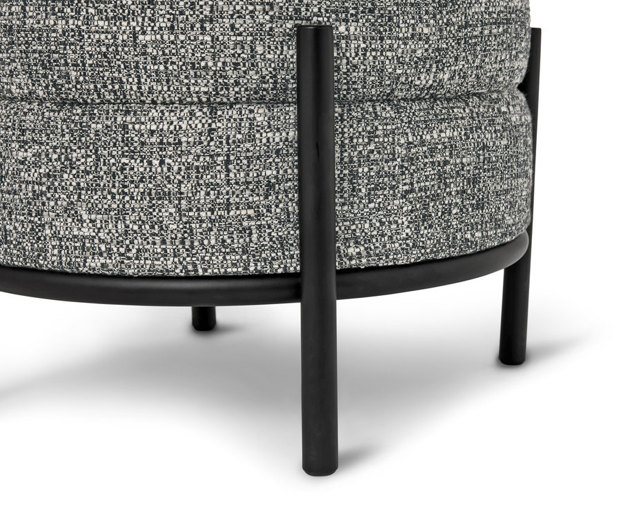 Gros plan d'un tabouret rond avec un revêtement en tissu à motifs gris et des pieds en métal noir.