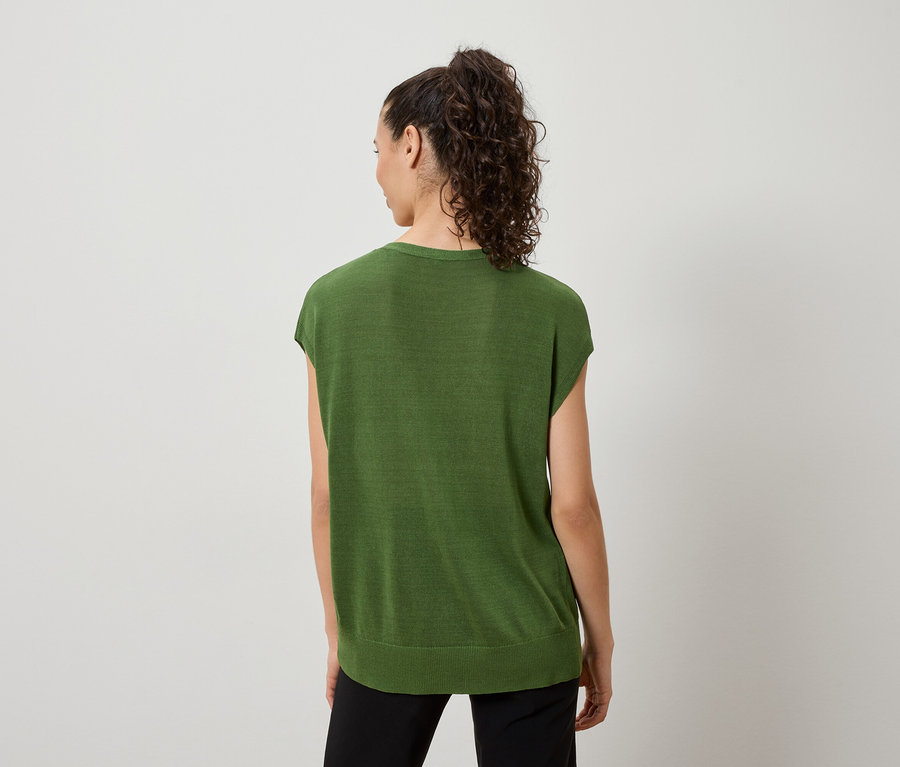 Vue arrière d'une femme avec une queue de cheval bouclée, portant un haut vert à manches courtes et un pantalon noir.