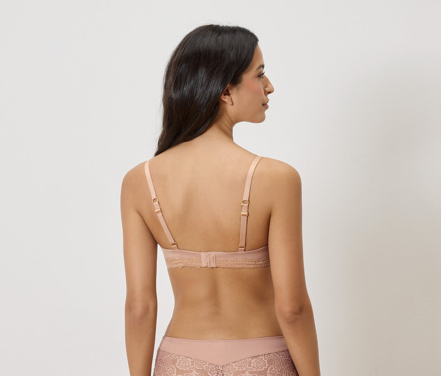 Vue arrière d'une femme aux longs cheveux foncés portant un soutien-gorge beige clair et des sous-vêtements assortis.