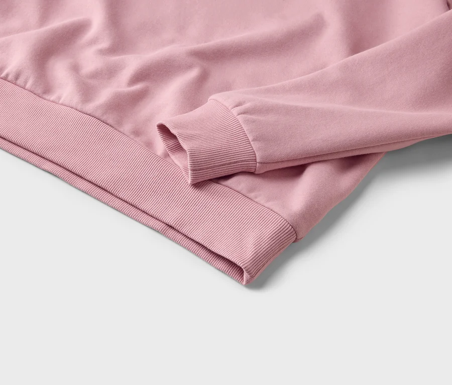 Gros plan d'un sweat-shirt rose, montrant le poignet et l'ourlet côtelés.