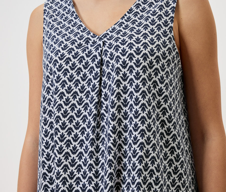 Gros plan d'une femme portant une robe sans manches à motif bleu et blanc.