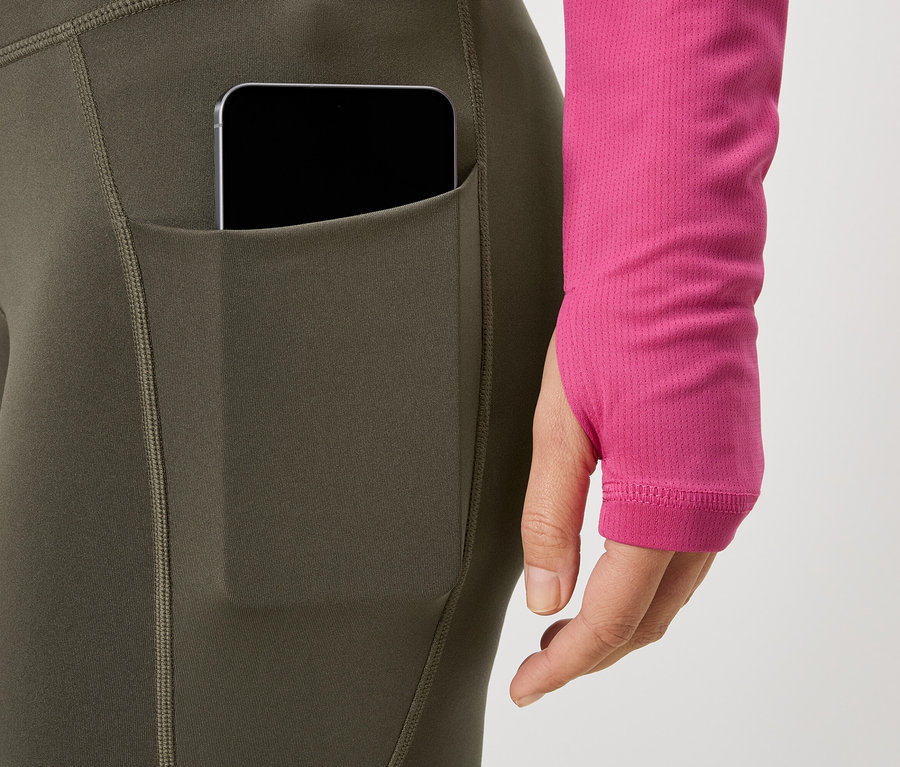 Femme portant des leggings avec poche pour téléphone et un haut rose.