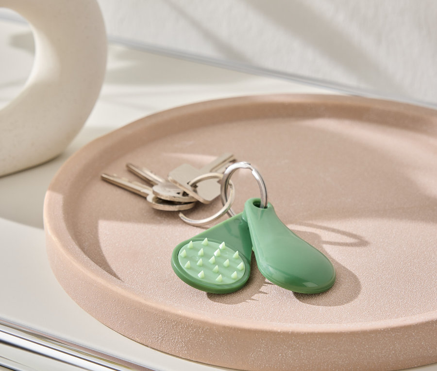 Clés et porte-clés verts posés sur une assiette rose.