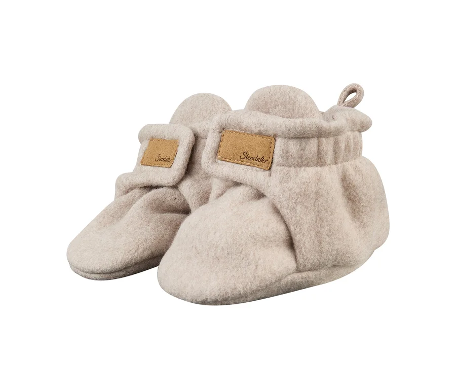 Une paire de chaussons de bébé beige clair en matière douce et feutrée, avec un rabat à scratch et une étiquette marron « Sterntaler ».