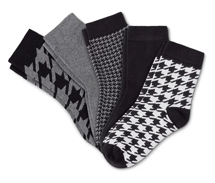 Cinq chaussettes noires, grises et blanches, certaines avec un motif pied-de-poule, étalées en éventail sur un fond blanc.