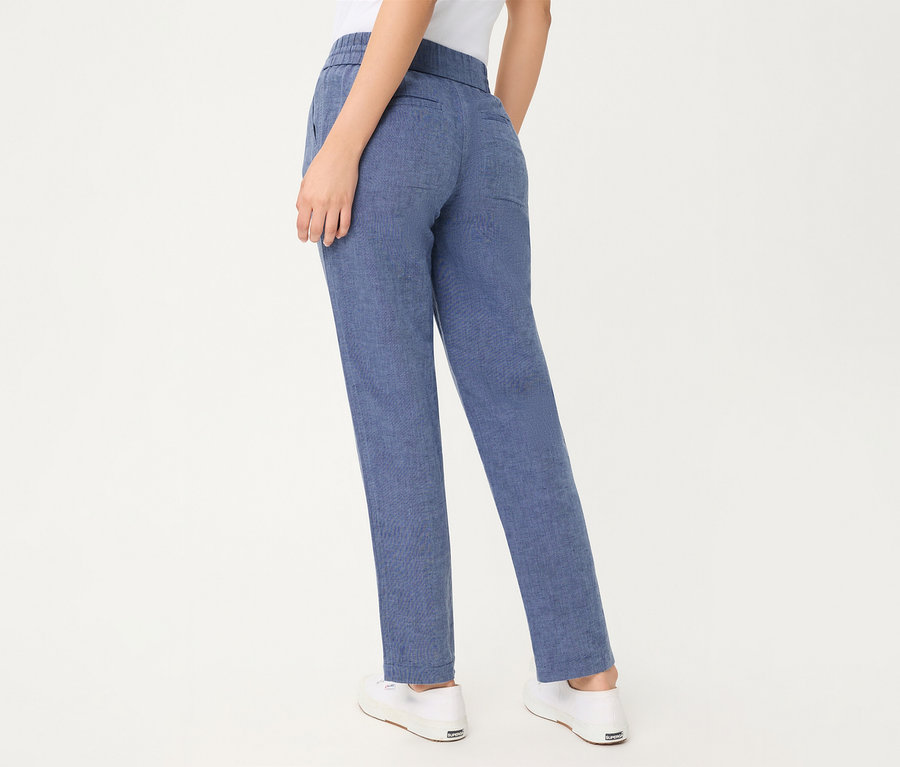 Personne vue de dos, portant un jean Olsen cropped bleu et des baskets blanches.