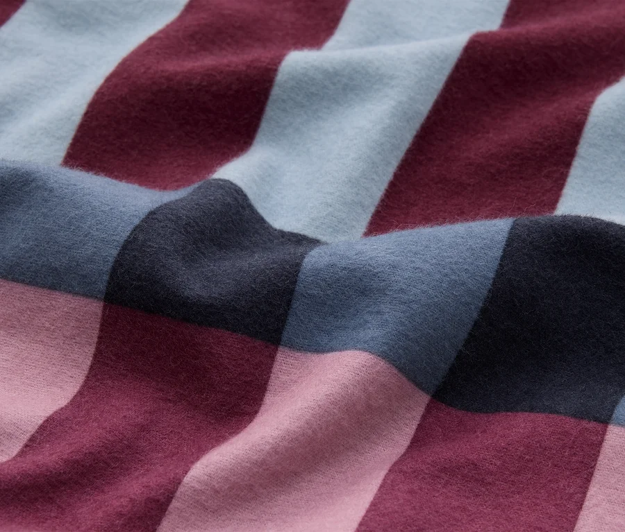Tissu doux à grand motif à carreaux en bleu clair, rouge foncé, gris foncé et rose clair, avec de légers plis.