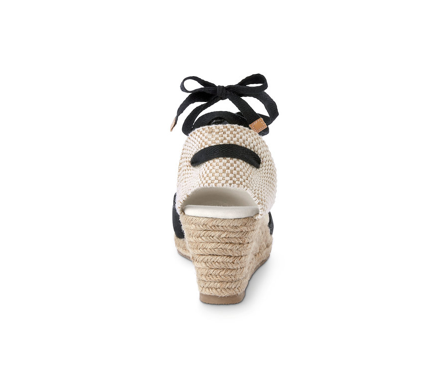 Détail de l'arrière d'une espadrille compensée avec un ruban noir et un talon tressé beige.