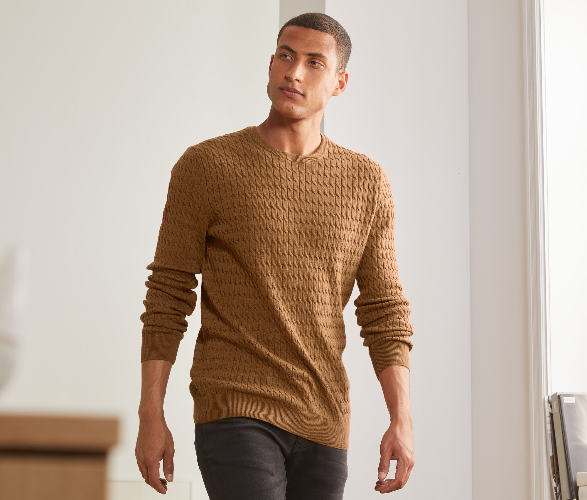 Un homme porte un pull en maille jaune moutarde chiné.