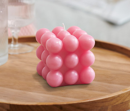 Sur une table en bois se trouvent 2 bougies bubble, un verre d'eau et une carafe.