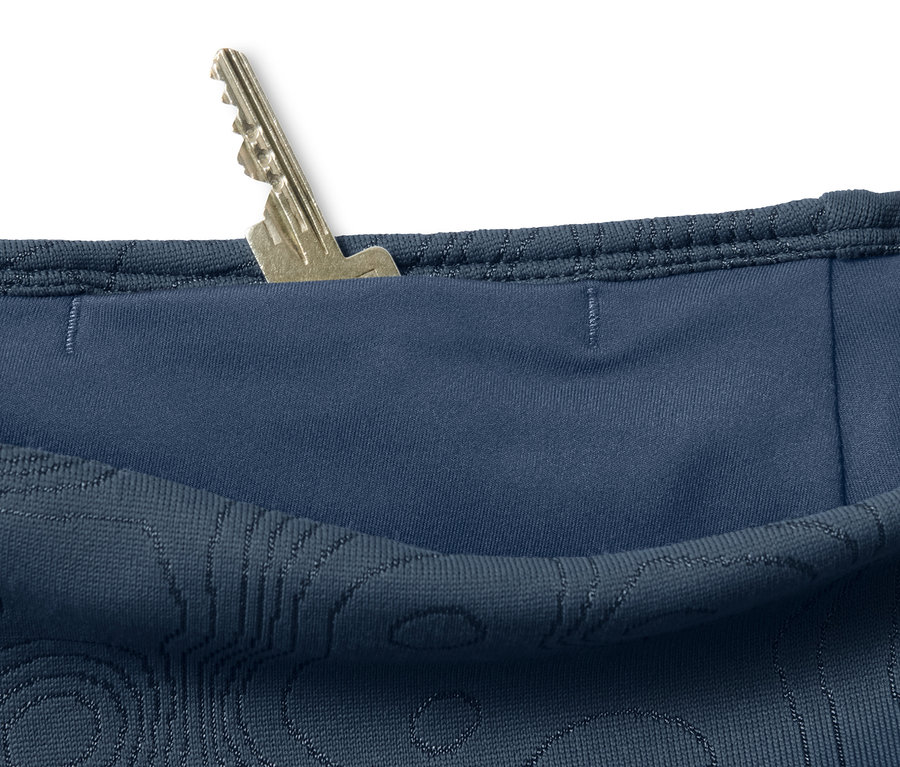 Détail d'un legging doux bleu avec une clé dans la poche.