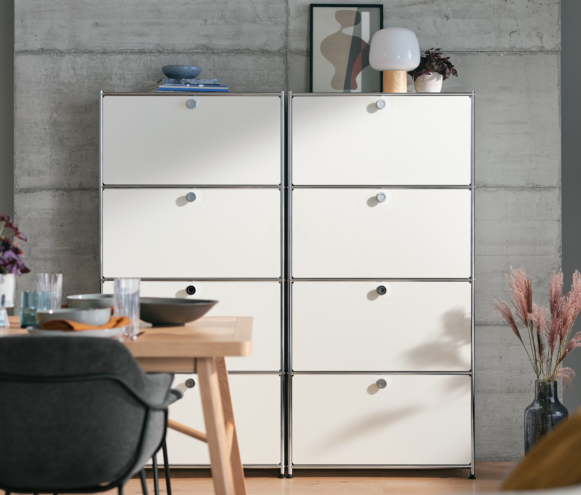 Deux meubles hauts en métal « CN3 » blancs à 4 abattants placés côte à côte derrière une table à manger.