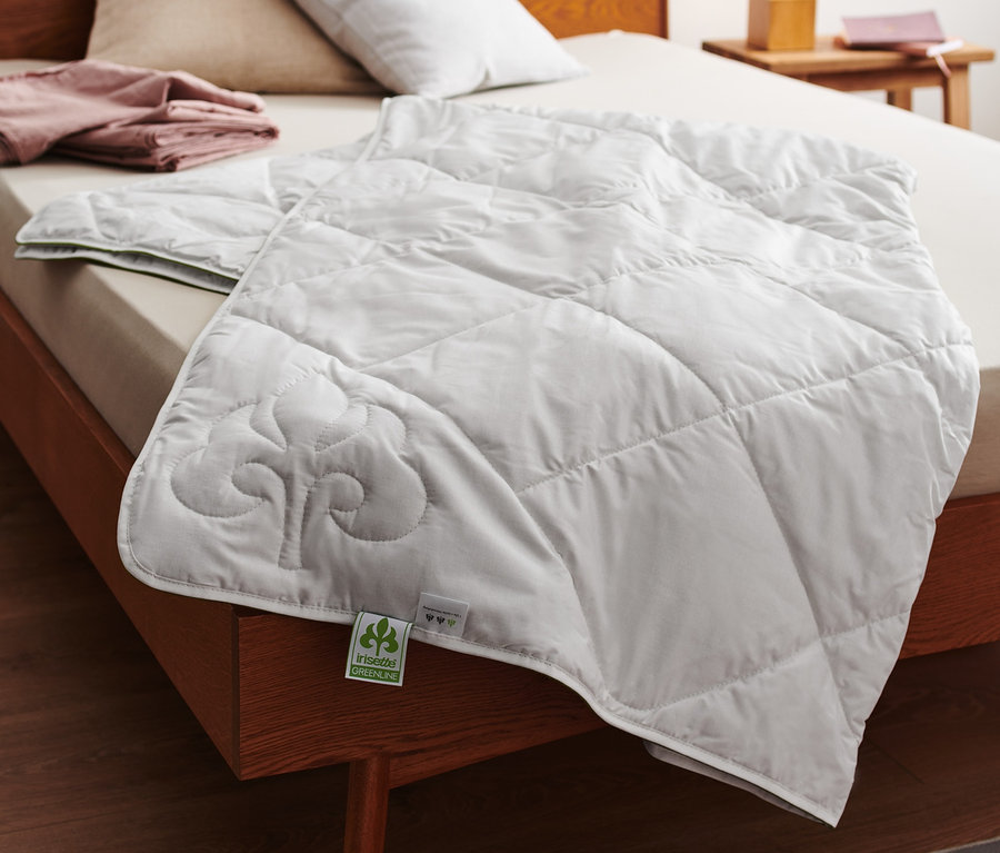 Sur un lit, une couette d'été surpiquée en coton et lin irisette® greenline blanche.