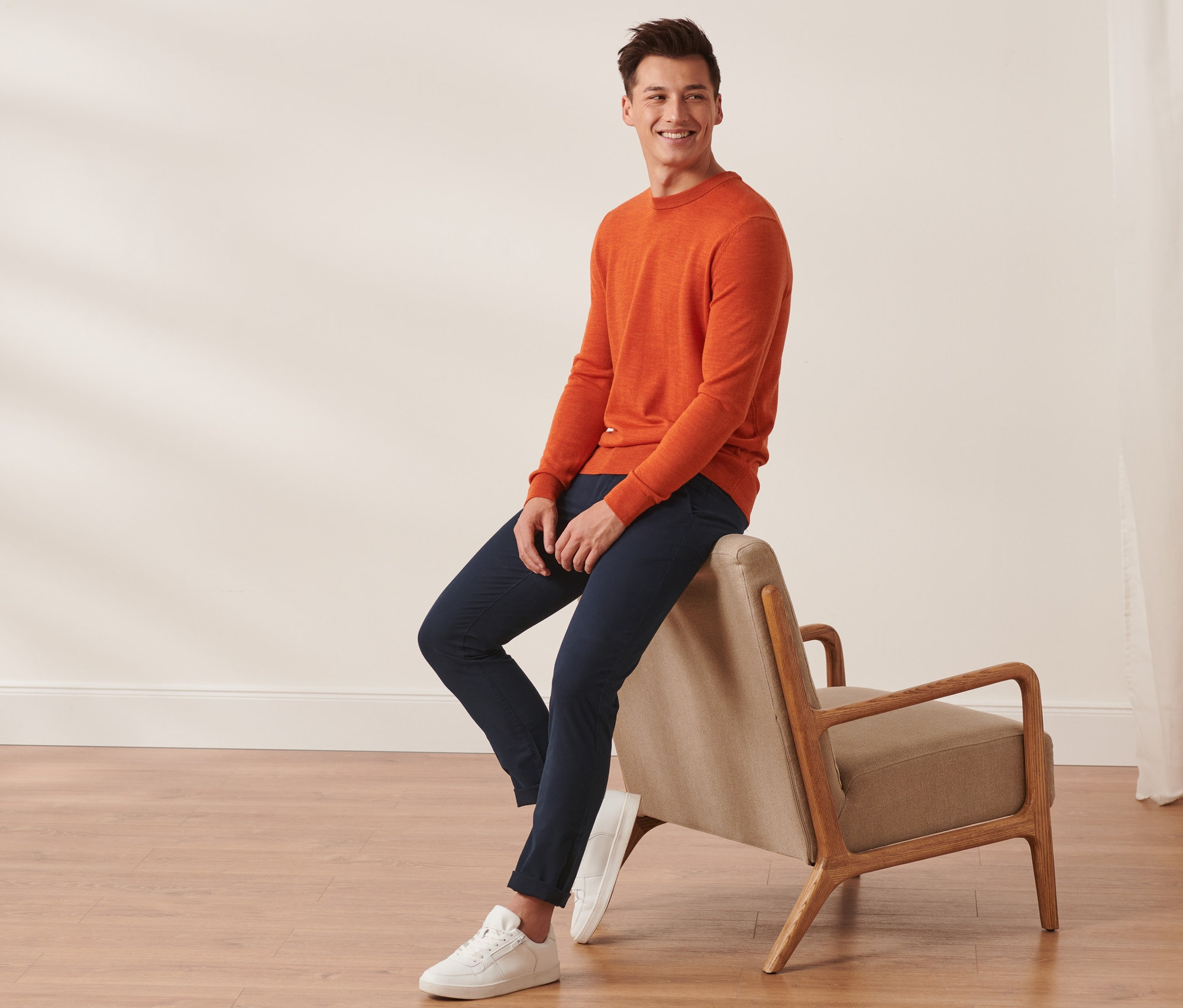 Un homme est assis sur une chaise et porte un pantalon chino bleu foncé.