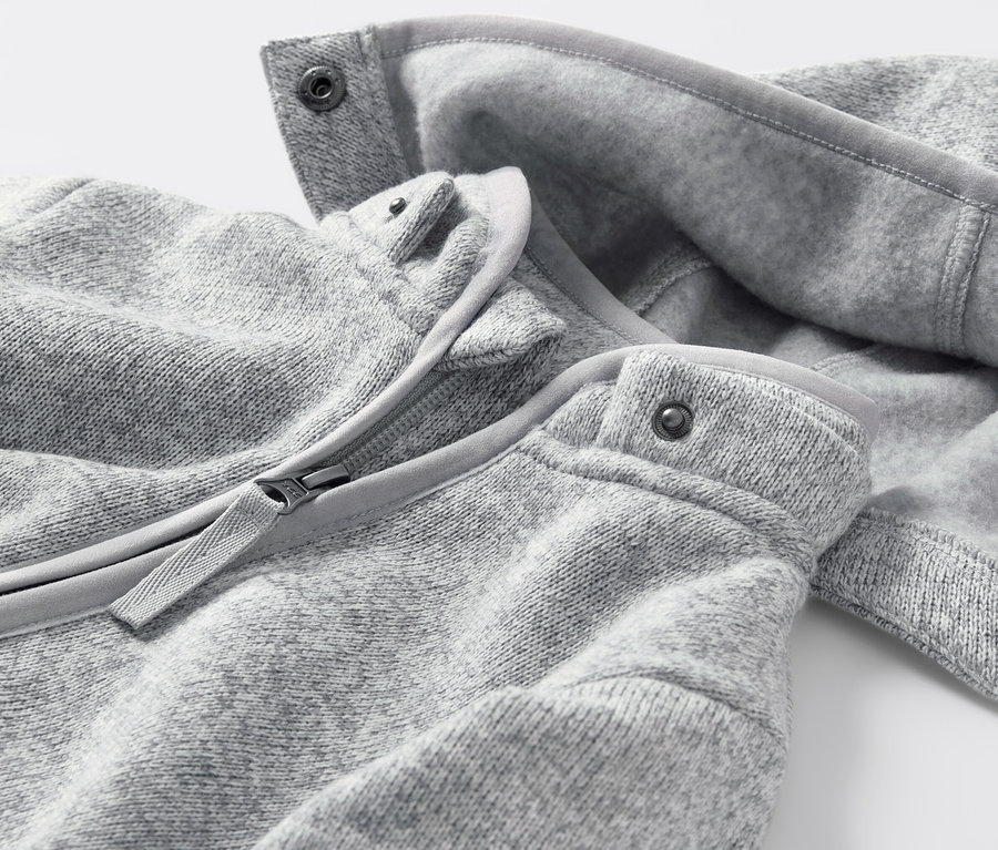 Gros plan sur une combinaison en polaire tricotée pour bébé avec fermeture éclair et boutons-pression.