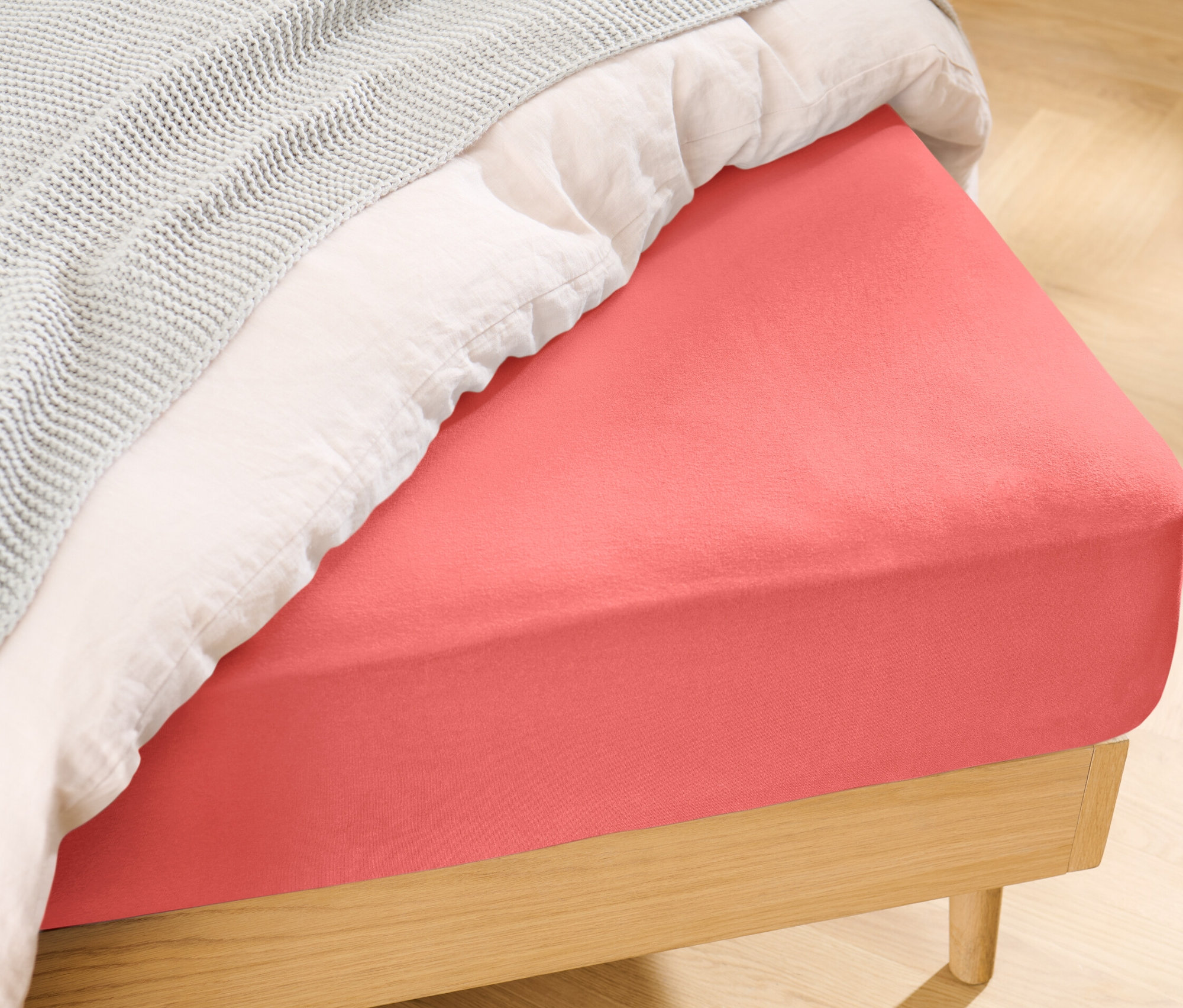 Gros plan d'un lit avec un drap-housse en jersey orange de taille standard.
